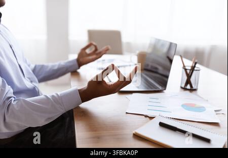 Cropped of office worker sitting at workdesk, meditating Stock Photo