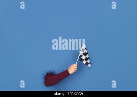 Hand holding checkered flag over blue background Stock Photo