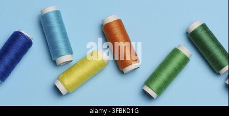 Multicolored spools of sewing threads on a blue background, top view Stock Photo