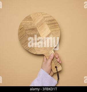 Woman's hand holding empty round wooden cutting board, top view Stock Photo