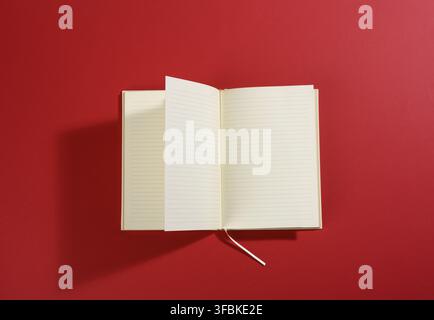 Open notebook with blank white sheets on red background, top view Stock Photo