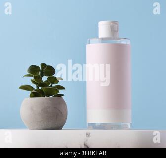 Blank bottle for cosmetics with pink paper label on a blue background. Bottle for tonic, gel Stock Photo