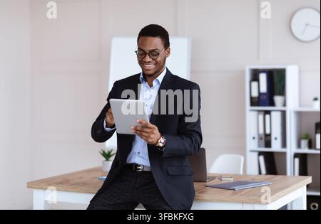 Joyful african american businessman using newest digital tablet Stock Photo