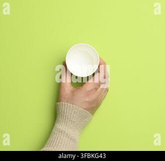 Female hand holding empty paper disposable cup on green background, concept eco-friendly, zero waste, top view Stock Photo
