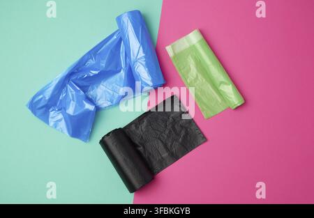 Three rolled up rolls with plastic garbage bags on a green pink background, top view Stock Photo
