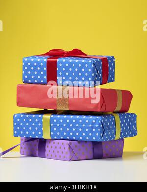 A stack of gift boxes tied with a ribbon on a yellow background Stock Photo