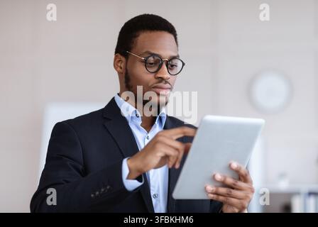 Serious black entrepreneur in glasses using digital tablet Stock Photo