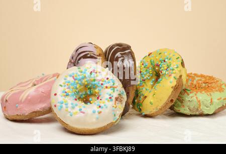 Stack of donuts with different toppings and glazes, beige background Stock Photo
