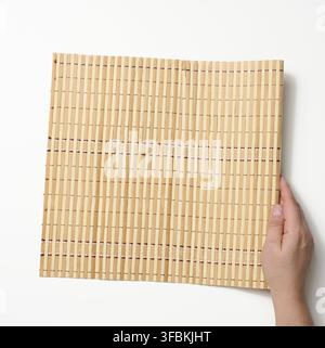 Female hand holding bamboo mat on white background Stock Photo