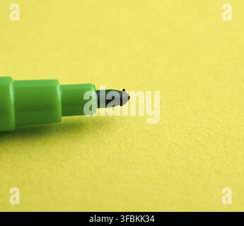 Green felt-tip pen on a yellow background, macro Stock Photo