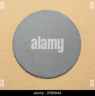 Empty black round slate kitchen board on a brown background, top view Stock Photo
