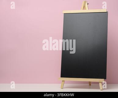 Empty black slate board on white table, pink background. Place for the inscription of the announcement Stock Photo
