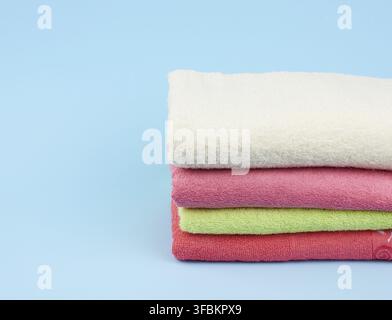 Stack of colored cotton terry folded towels on a blue background, copy space Stock Photo