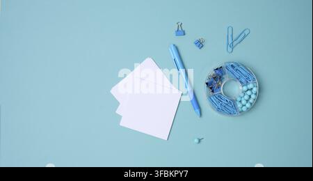 Stack of white square sheets of paper for notes, stationery on blue background, top view Stock Photo