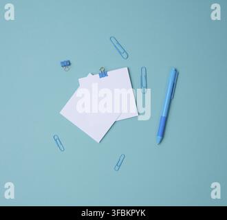 Stack of white square sheets of paper for notes, stationery on blue background, top view Stock Photo