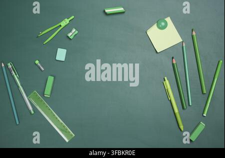 School supplies on empty green chalk board, top view. Back to school, copy space Stock Photo