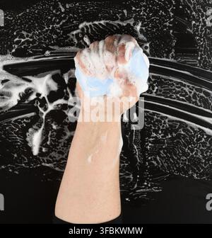 Process of washing hands with blue soap, parts of the body in white foam on a black background, hygiene concept Stock Photo