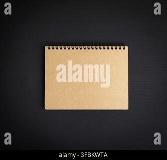 Blank notepad with brown sheets on a black wooden background, top view Stock Photo