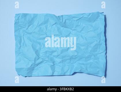 Crumpled rectangular sheet of blue paper on a blue background, top view. Place for inscription Stock Photo