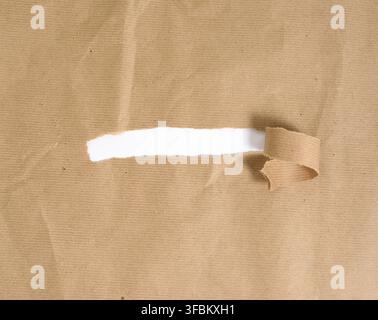 Brown sheet of paper with a torn hole and a curled strip, white background Stock Photo