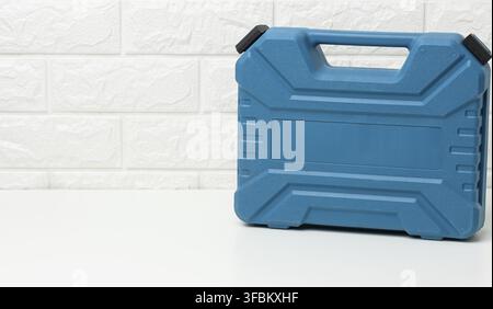 Closed blue plastic tool case stands on a white table Stock Photo
