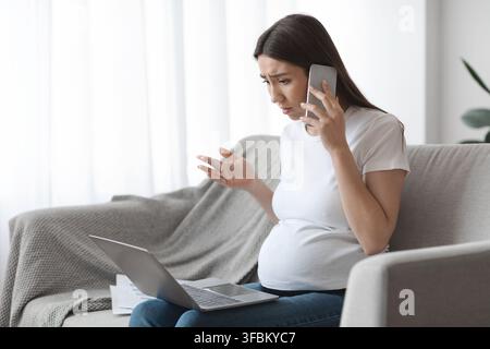 Stressed Pregnant Woman Working With Laptop And Talking On Cellphone At Home Stock Photo