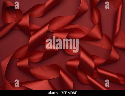 Curled red silk ribbon on a red background, festive background Stock Photo