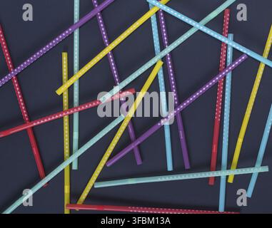 Multi-colored plastic tubes in a white polka-dot for drinks are scattered on a black background Stock Photo