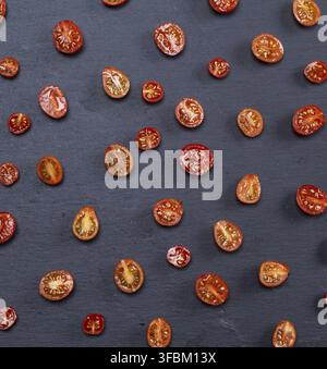 Ripe red cherry tomatoes cut in half on black background Stock Photo