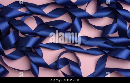 Curled blue silk ribbon on a pink background, festive background, top view Stock Photo
