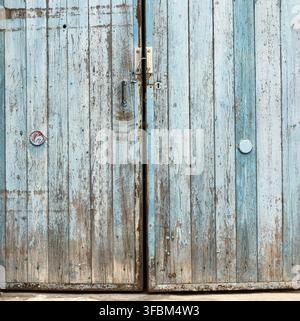 Fragment of very old wooden door with blue cracked paint, parallel boards, full frame Stock Photo