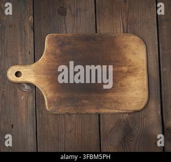 Very old empty wooden rectangular cutting board, top view, brown wooden background Stock Photo