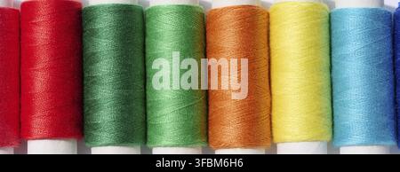 Multicolored spools of sewing threads on a white background, top view Stock Photo
