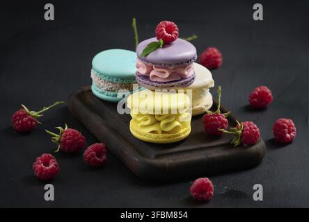 A stack of multi-colored macaroons on a wooden board. Delicious dessert Stock Photo