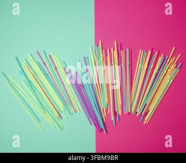 Stack of multi-colored plastic tubes for a cocktail on a multi-colored background, concept of environmental pollution by objects that decay in the gro Stock Photo