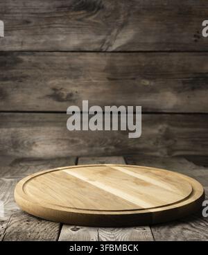 Empty round wooden cutting kitchen board on wooden background, pizza board Stock Photo