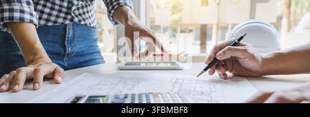 Engineer Hand Drawing Plan On Blue Print with architect equipment discussing the floor plans over blueprint architectural plans at table in a modern o Stock Photo
