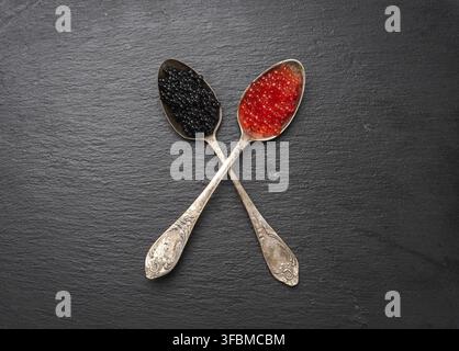Grainy caviar of paddlefish fish and red chum salmon caviar in a spoon, black background, top view Stock Photo