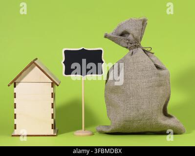 Mini wooden wooden house and chalk pointer on a green background. Real estate purchase concept, mortgage and home renovation Stock Photo