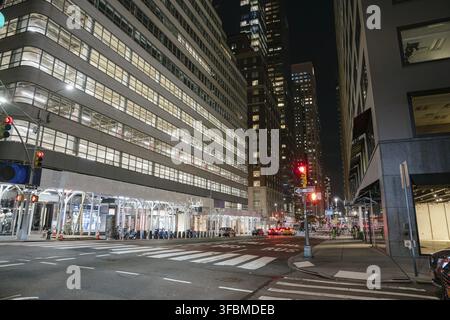 New York City, New York, USA - 07.30.2024: A modern office building with large glass windows is brightly lit at night on a New York City street corner Stock Photo