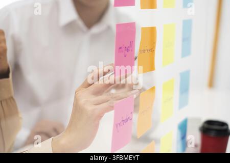 Creative group of business people brainstorming use sticky notes to share idea on glass window or table in office Stock Photo