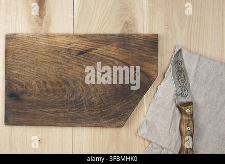 Old empty wooden rectangular cutting board and knife, top view, beige wooden background Stock Photo