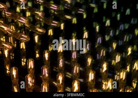 Infinite reflection of glowing filament light bulbs inside an infinity mirror, showing repeating color shifting light patterns. Stock Photo