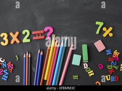 Wooden multi-colored pencils, plastic numbers on a black background, concept back to school, copy space Stock Photo