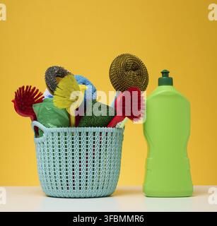 Plastic basket with brushes, disinfectant in a bottle on a yellow background Stock Photo