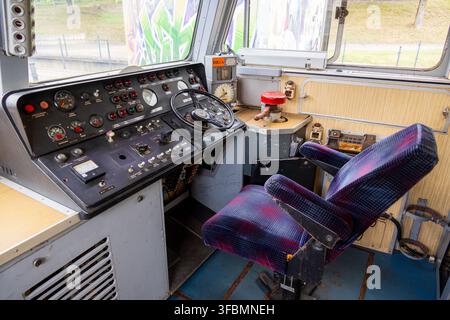 View of the interior of a vintage train locomotive cab featuring a control panel, gauges, and a driver seat at Railway Park in Vilnius, Vilniaus apskr Stock Photo