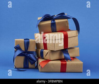 Rectangle box wrapped in brown kraft paper and tied with a silk blue and red ribbon, gift on a dark blue background Stock Photo