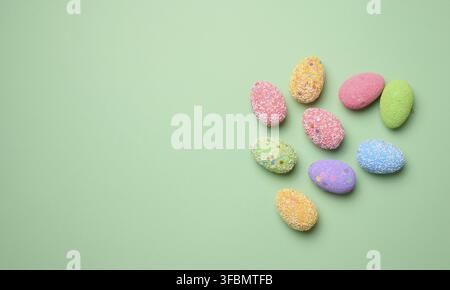 Multicolored decorative Easter eggs on green background, top view. Copy space Stock Photo