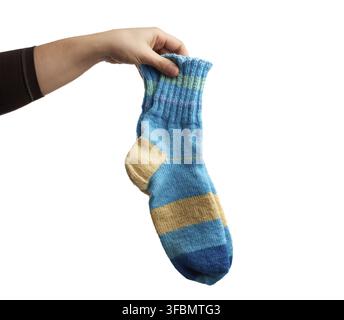 Female hand holds a pair of knitted woolen socks, warm clothes, item is isolated on a white background Stock Photo