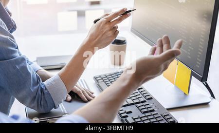 Young startup Programmers Sitting At Desks Working On Computers screen for Developing programming and coding to find solution to problem on New Applic Stock Photo